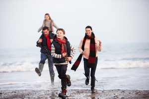 family running along the beach on an autumn day